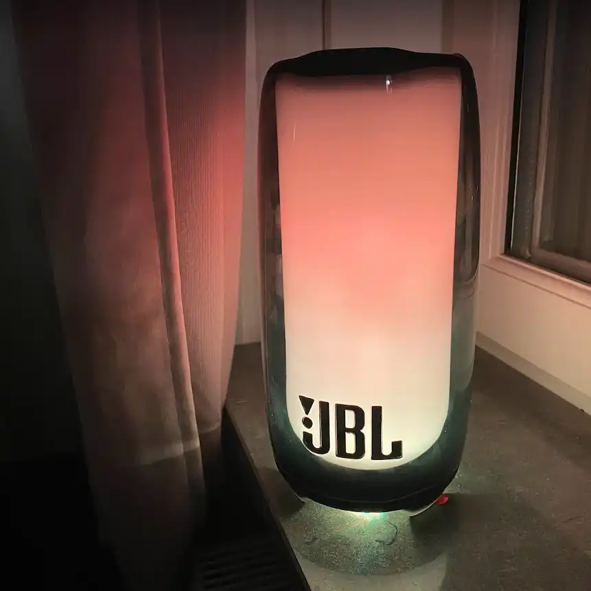 JBL Pulse lyser rosa och gult på en svart fönsterbänk