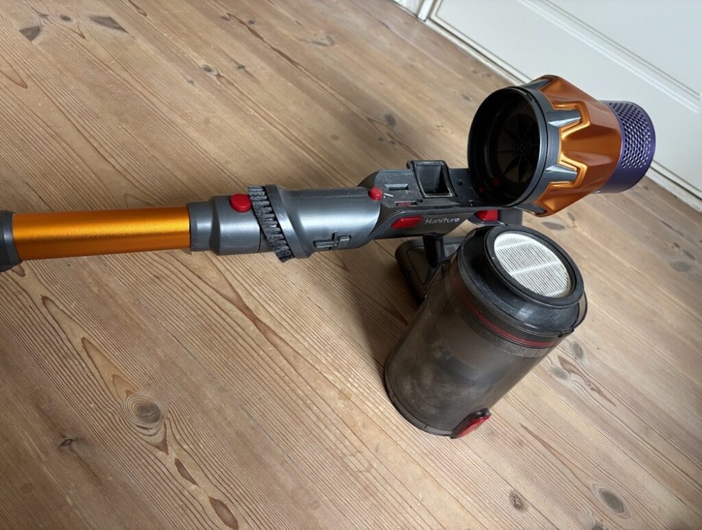 Dammbehållaren på Maxlager Ultra X7 bredvid skaftdammsugaren